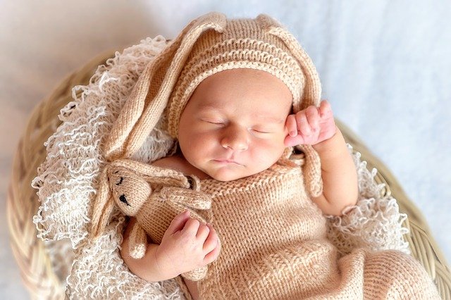a baby sleeps with a doll