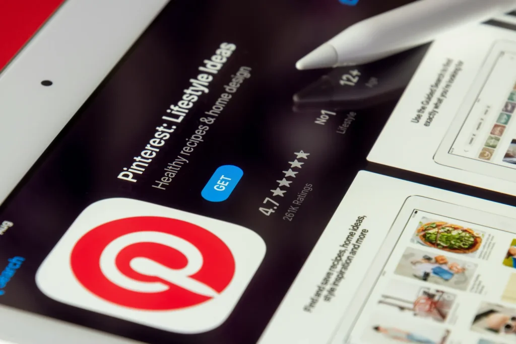 Close-up view of a tablet screen displaying the App Store page for Pinterest, showcasing its signature red "P" logo, a blue "GET" button, and star rating details. This is in "Pinterest Product Pin Image Requirements" article in Dropicts.com website.